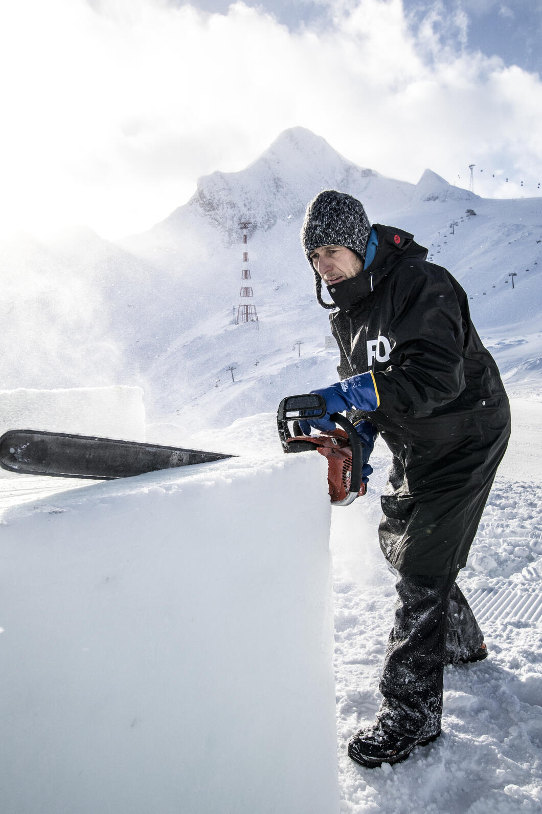 Mit der Motorsäge bearbeitet der Künstler und Bildhauer Max Seibald die Eisblöcke für seine ICE CAMP-Skulpturen. Er ist seit dem ersten ICE CAMP im Winter 2006/2007 mit dabei. | © Kitzsteinhorn / Dominik Wartbichler